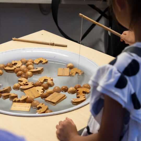子どもが木製の金魚すくいをしている様子